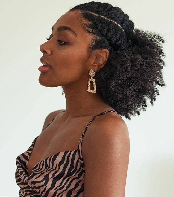 Woman with a voluminous side puff hairstyle and twisted braids on her scalp.