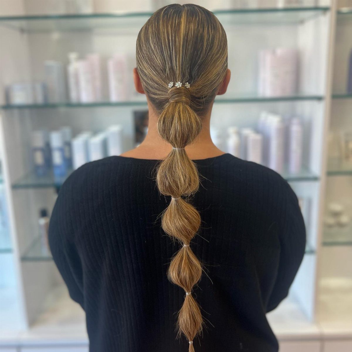 11 Picture Day Hair Ideas for Kids, from Braids to Bows 3 Blonde bubble ponytail hairstyle with decorative pins on a person wearing black.