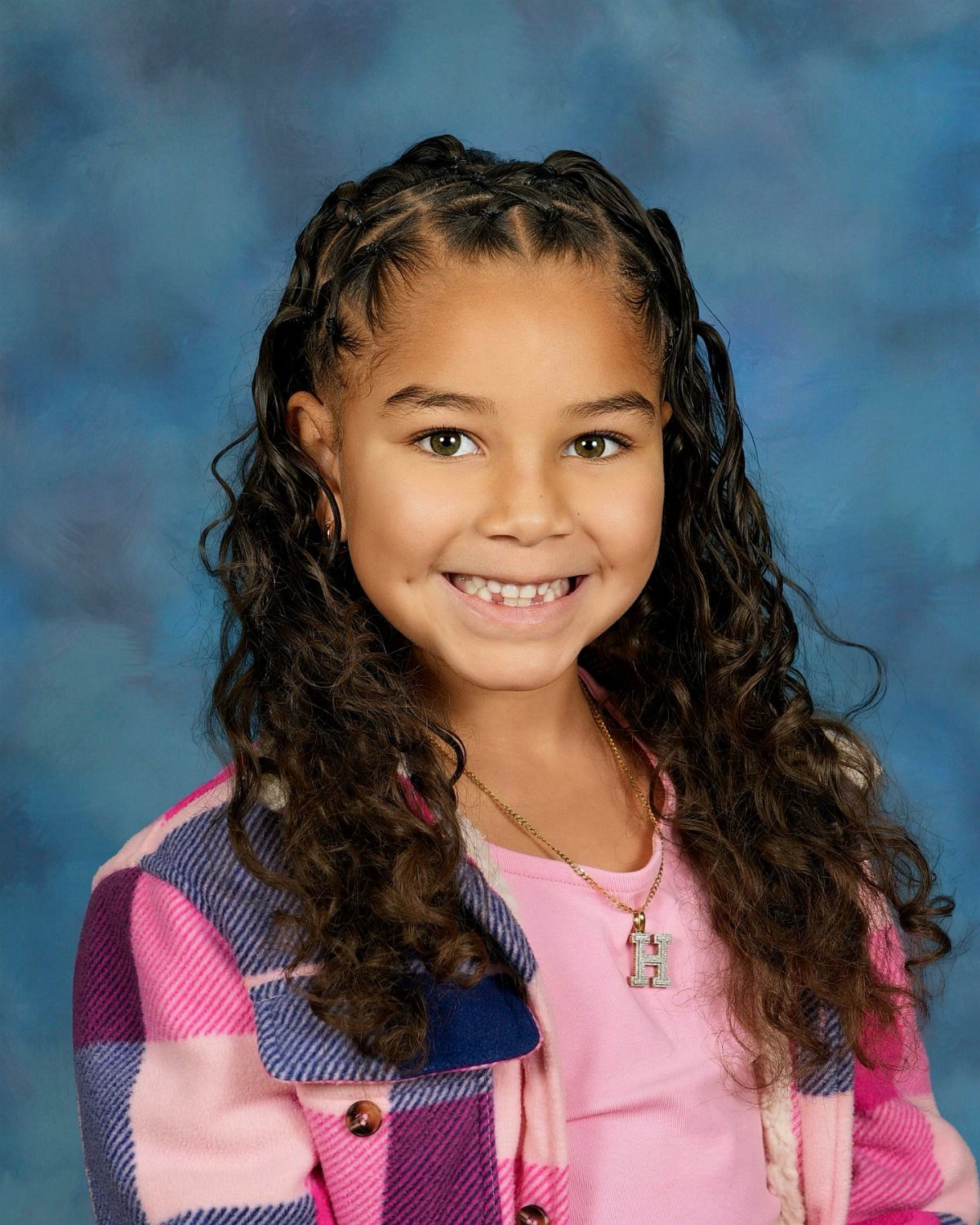11 Picture Day Hair Ideas for Kids, from Braids to Bows 8 Young girl with curly hair and crown braids posing for a school portrait.