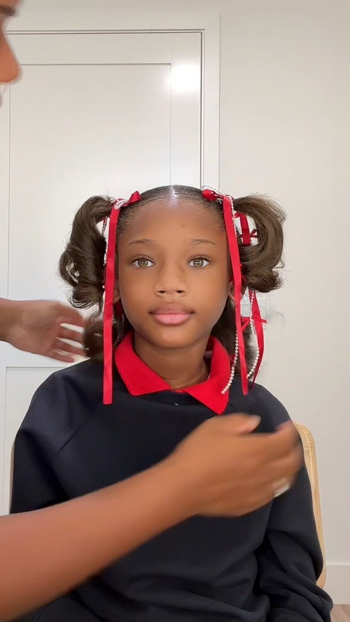 11 Picture Day Hair Ideas for Kids, from Braids to Bows 7 Young girl with curly pigtails and red ribbons wearing a school uniform.