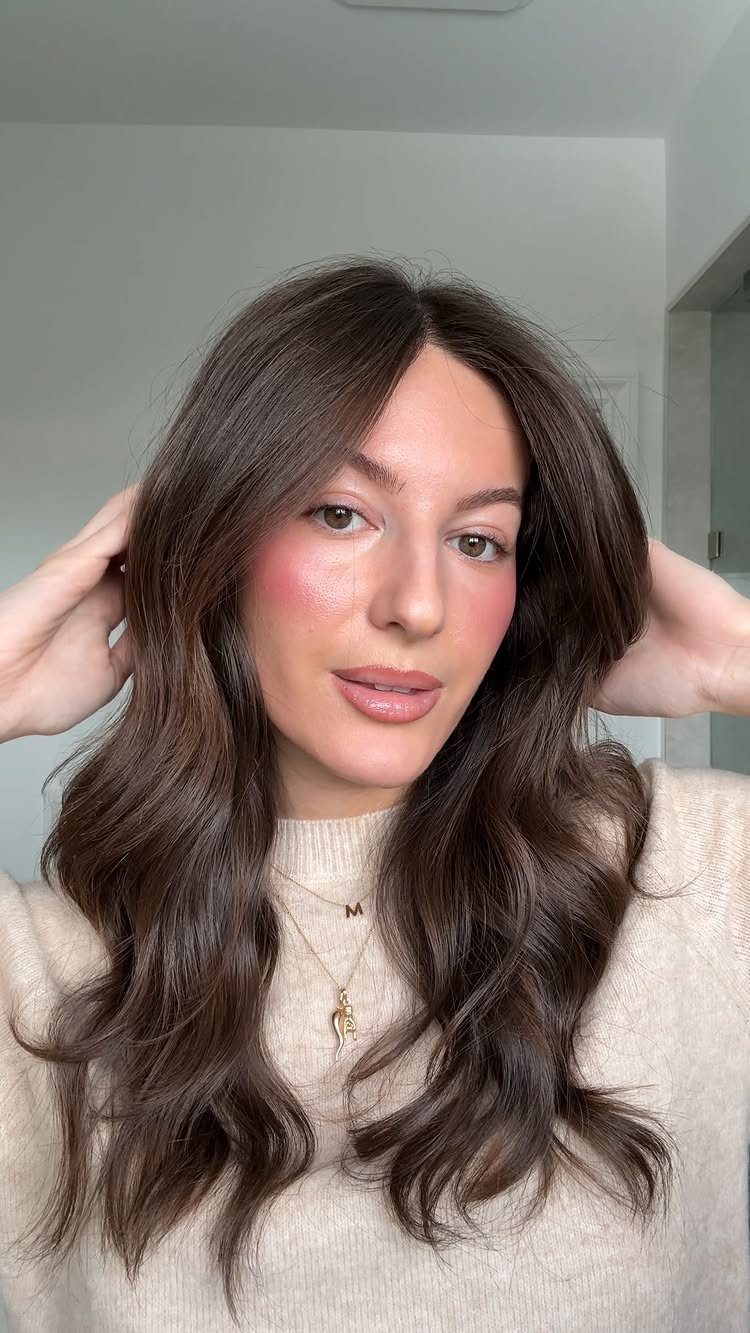 11 Picture Day Hair Ideas for Kids, from Braids to Bows 4 Woman with long brown hair styled in loose waves wearing a beige sweater