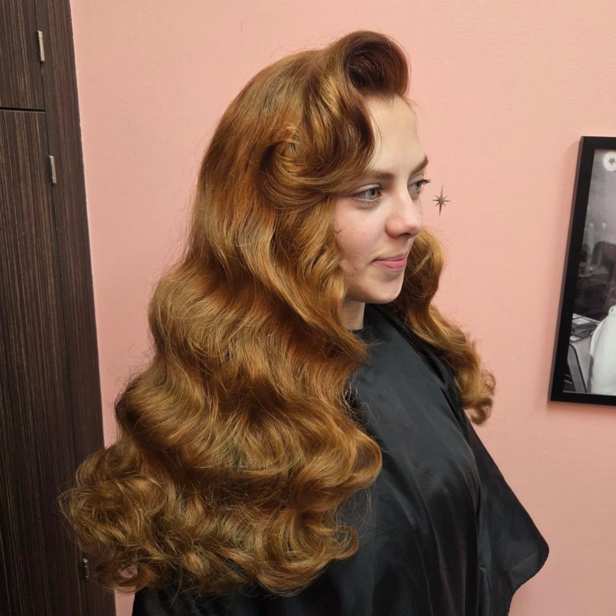 Pin Up Curls Hairstyles to Try: 6 Retro Ideas 5 Woman with voluminous strawberry blonde retro curls and waves wearing a black cape.
