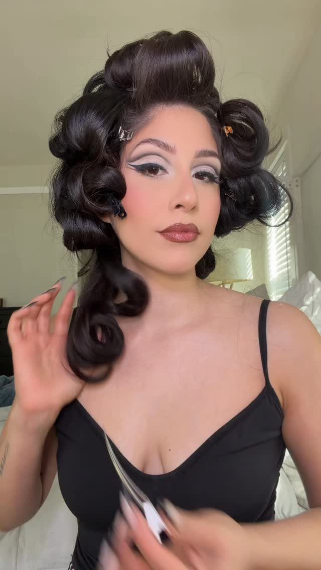 Pin Up Curls Hairstyles to Try: 6 Retro Ideas 1 Woman with dark hair styled in voluminous elevated pincurls and retro rolls.