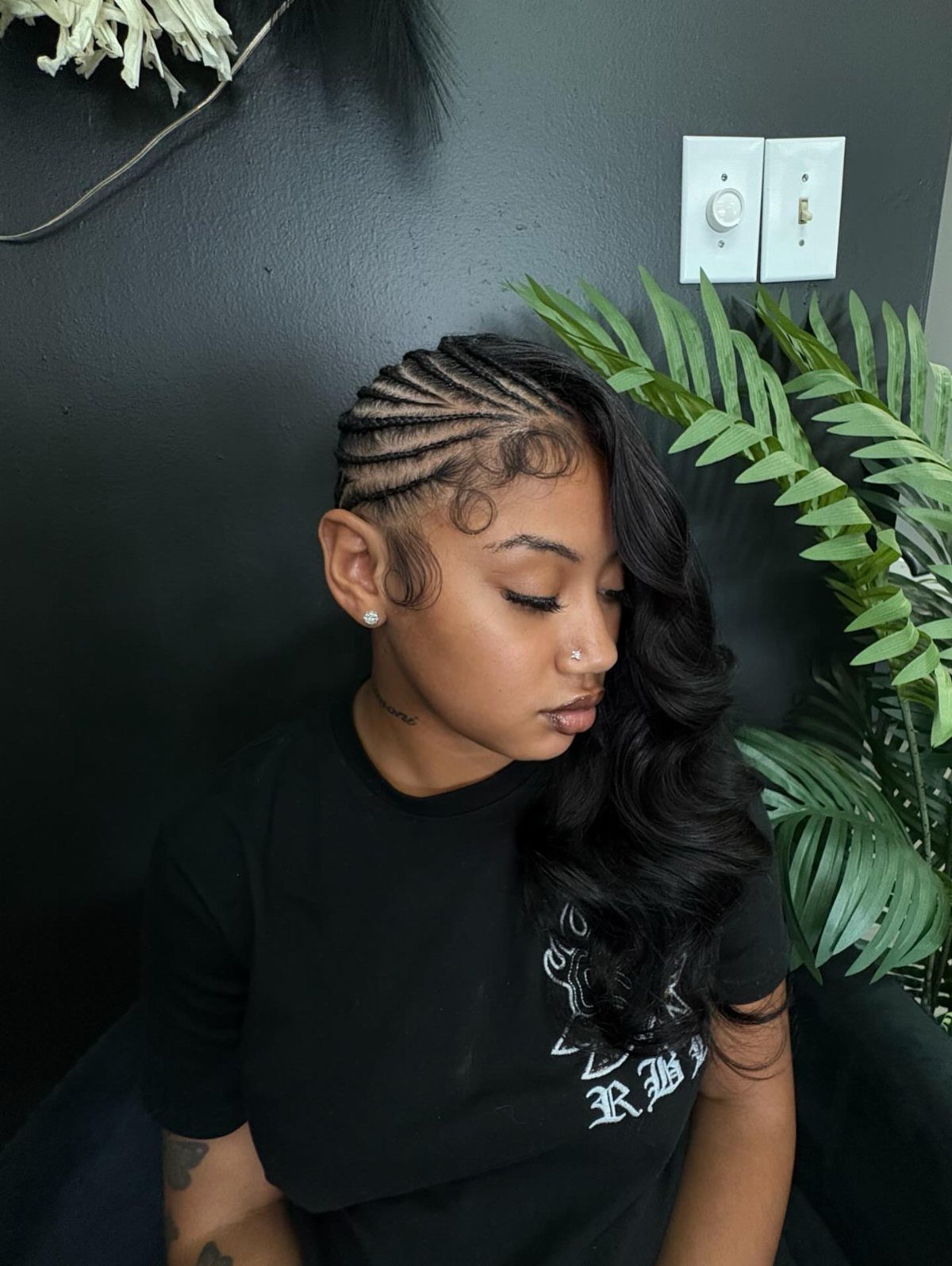 Quick Weave Styles with Braids: 18 Cornrow and Updo Ideas 5 Woman with side-swept cornrow braids and long wavy black hair flowing over shoulder.