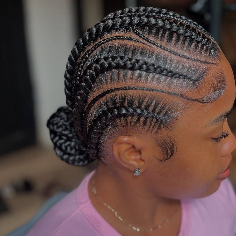 Quick Weave Styles with Braids: 18 Cornrow and Updo Ideas 2 Woman with curved stitch braids gathered into a neat braided bun at the back.