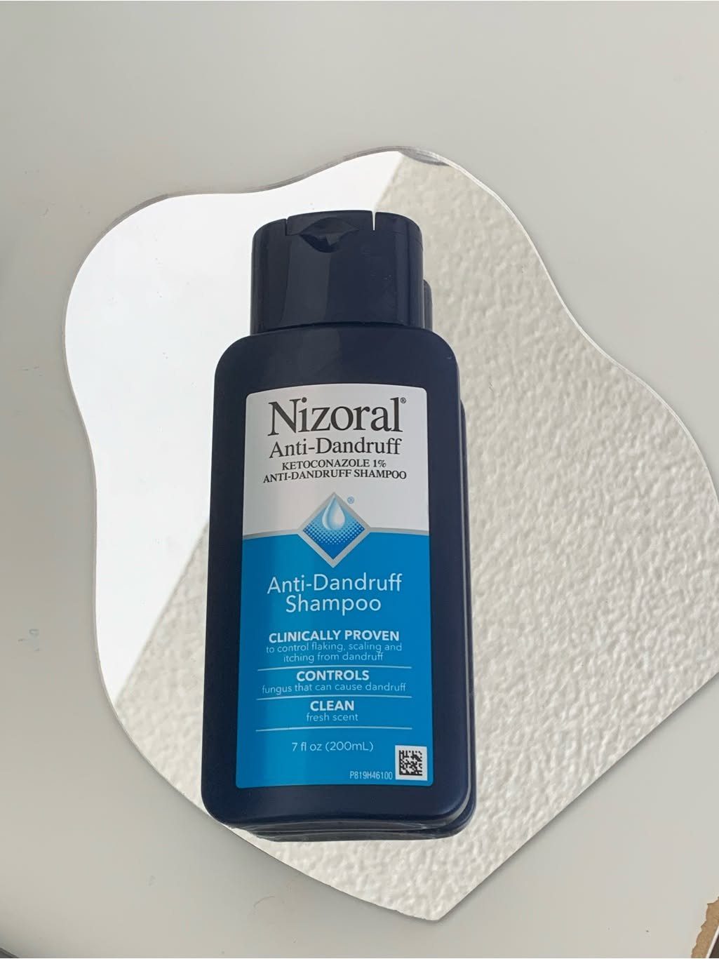 Scalp Care for Dandruff: 3 Ideas to Try at Home 1 Nizoral Anti-Dandruff Shampoo bottle on a white textured organic shaped background