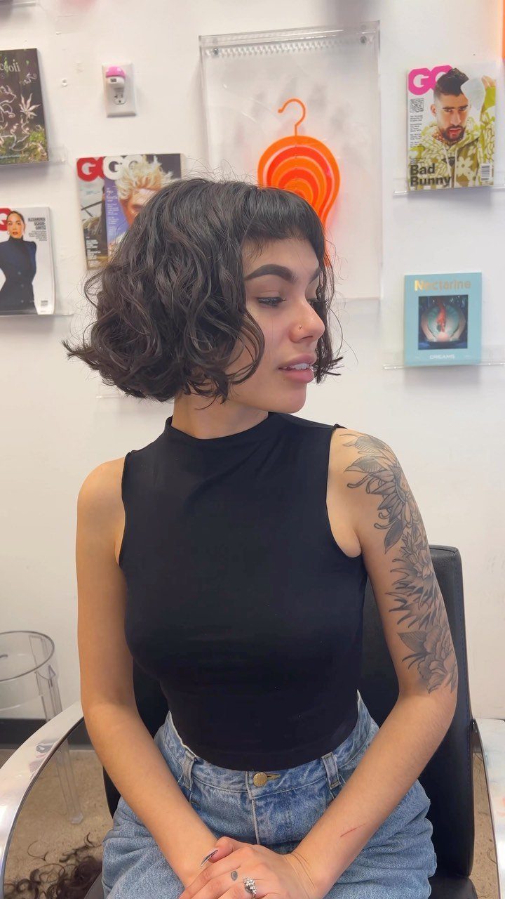 21 Short Curly Hair Styling Ideas for Every Texture 5 Woman with a short curly bob and curly bangs in a salon setting.