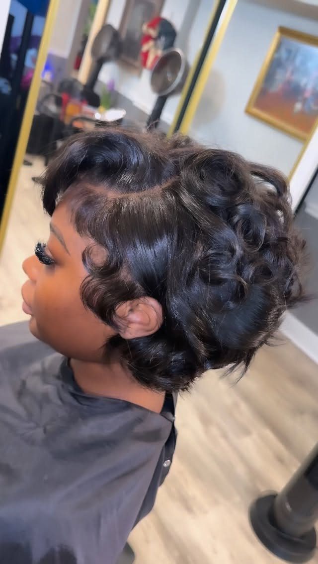 21 Short Curly Hair Styling Ideas for Every Texture 18 Person with short dark curly hair styled in glossy waves in a salon.