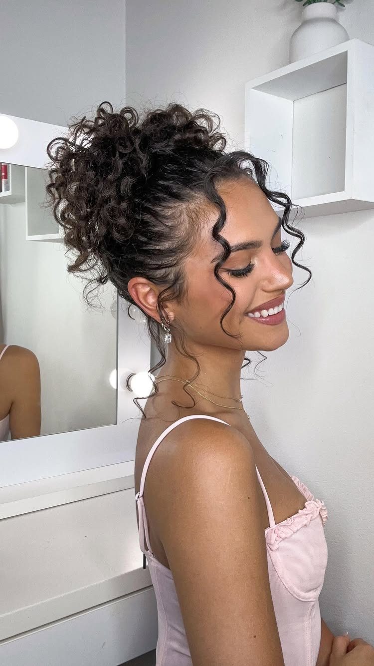 21 Short Curly Hair Styling Ideas for Every Texture 12 Woman with dark curly hair styled in a half-up top bun and tendrils.
