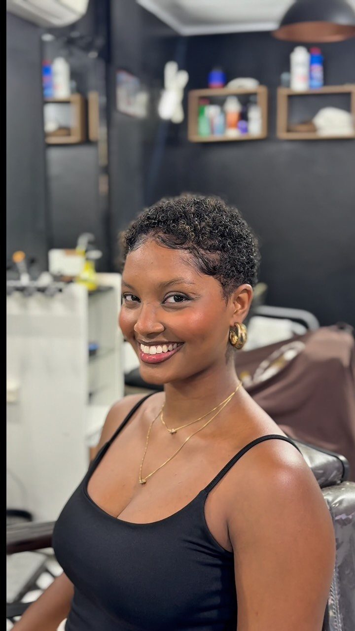 21 Short Curly Hair Styling Ideas for Every Texture 20 Woman with short curly hair and a tapered cut smiling in a salon