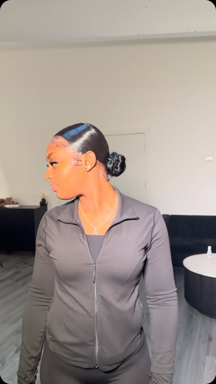 10 Sleek Hair Styles for Every Length and Occasion 2 Woman with dark hair styled in a sleek, slicked-back low bun wearing black jacket.