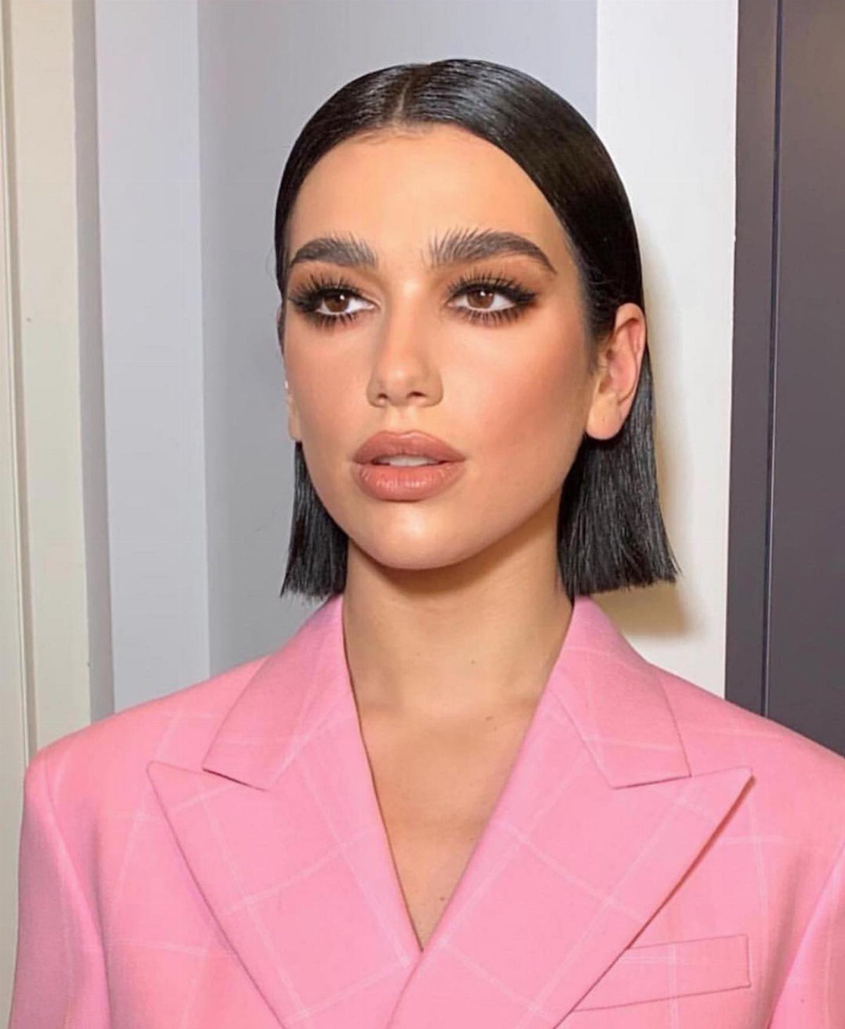 10 Sleek Hair Styles for Every Length and Occasion 10 Woman with a sleek black bob hairstyle and middle part wearing pink blazer