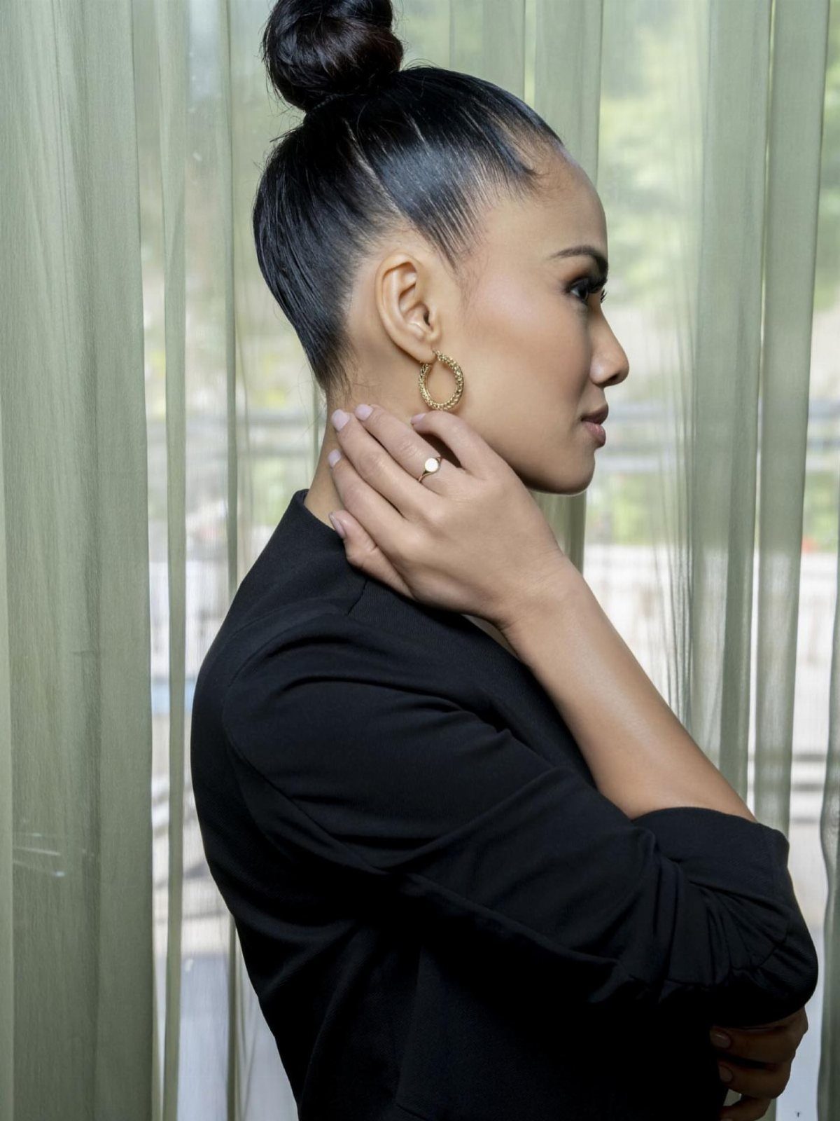10 Sleek Hair Styles for Every Length and Occasion 6 Woman with dark hair styled in a sleek top knot bun wearing black.