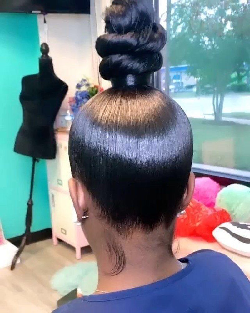 10 Sleek Hair Styles for Every Length and Occasion 7 Dark hair styled in a polished, wrapped top knot with a slicked-back finish.