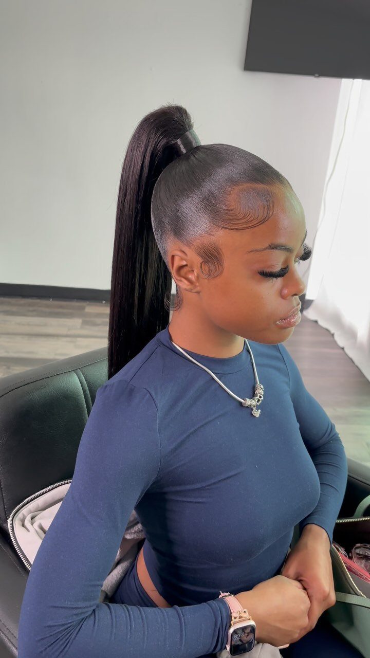 5 Sleek High Pony Ideas with Braids, Curls and Edges 4 Woman with a sleek high ponytail and styled edges wearing a navy blue shirt.
