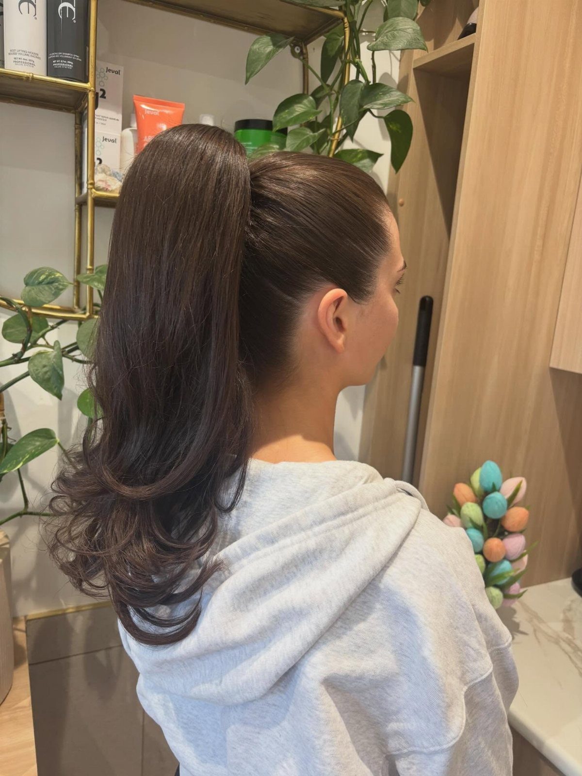 5 Sleek High Pony Ideas with Braids, Curls and Edges 5 Woman with dark brown hair styled in a sleek high ponytail with curled ends.