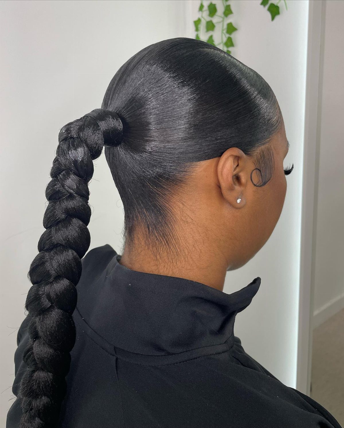 5 Slick Down Ponytail Ideas for Shine, Bangs and Curls 4 Slicked-back high ponytail with a thick braided extension on a person.