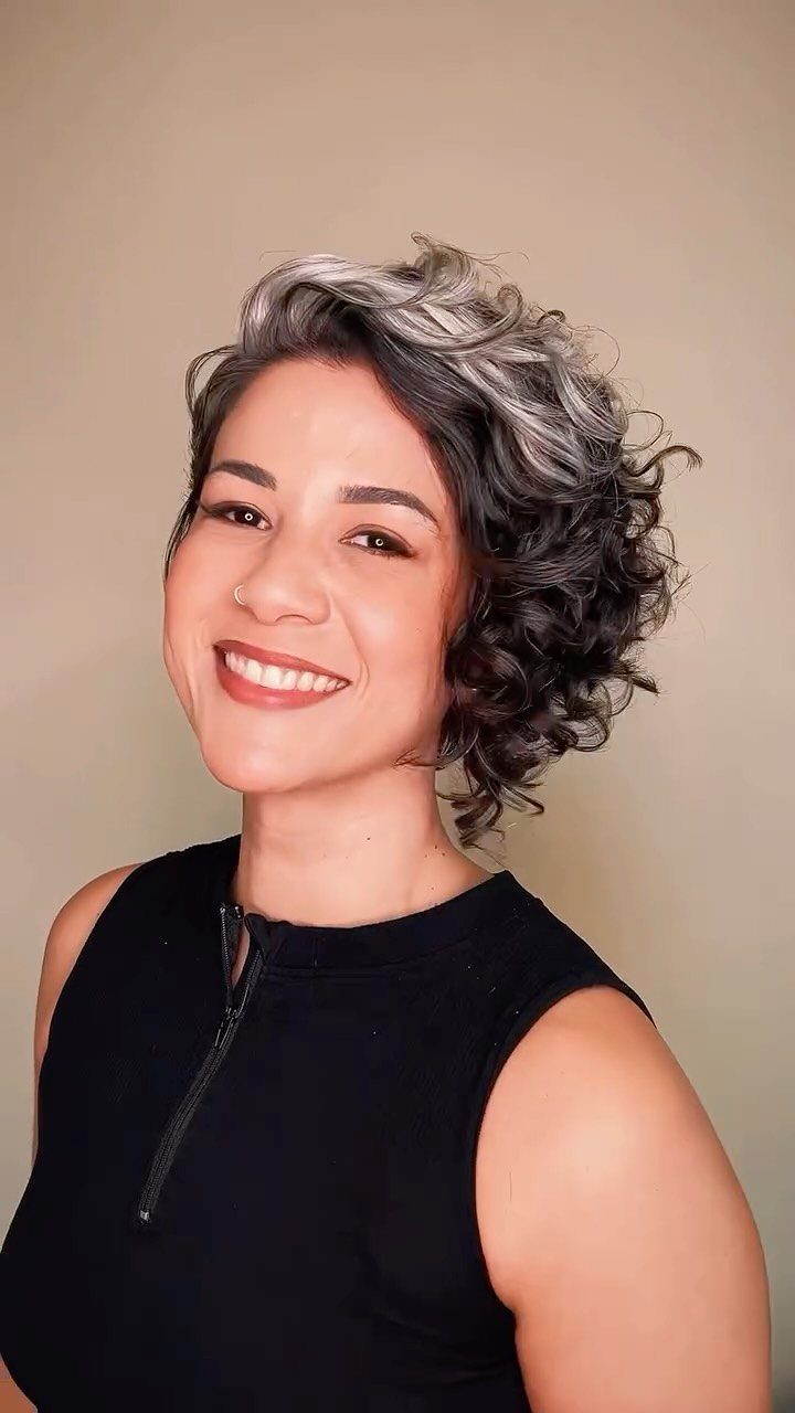 20 Thick Natural Hairstyles for Every Length and Mood 13 Woman with a short, curly bixie haircut in grey and brown tones smiling.