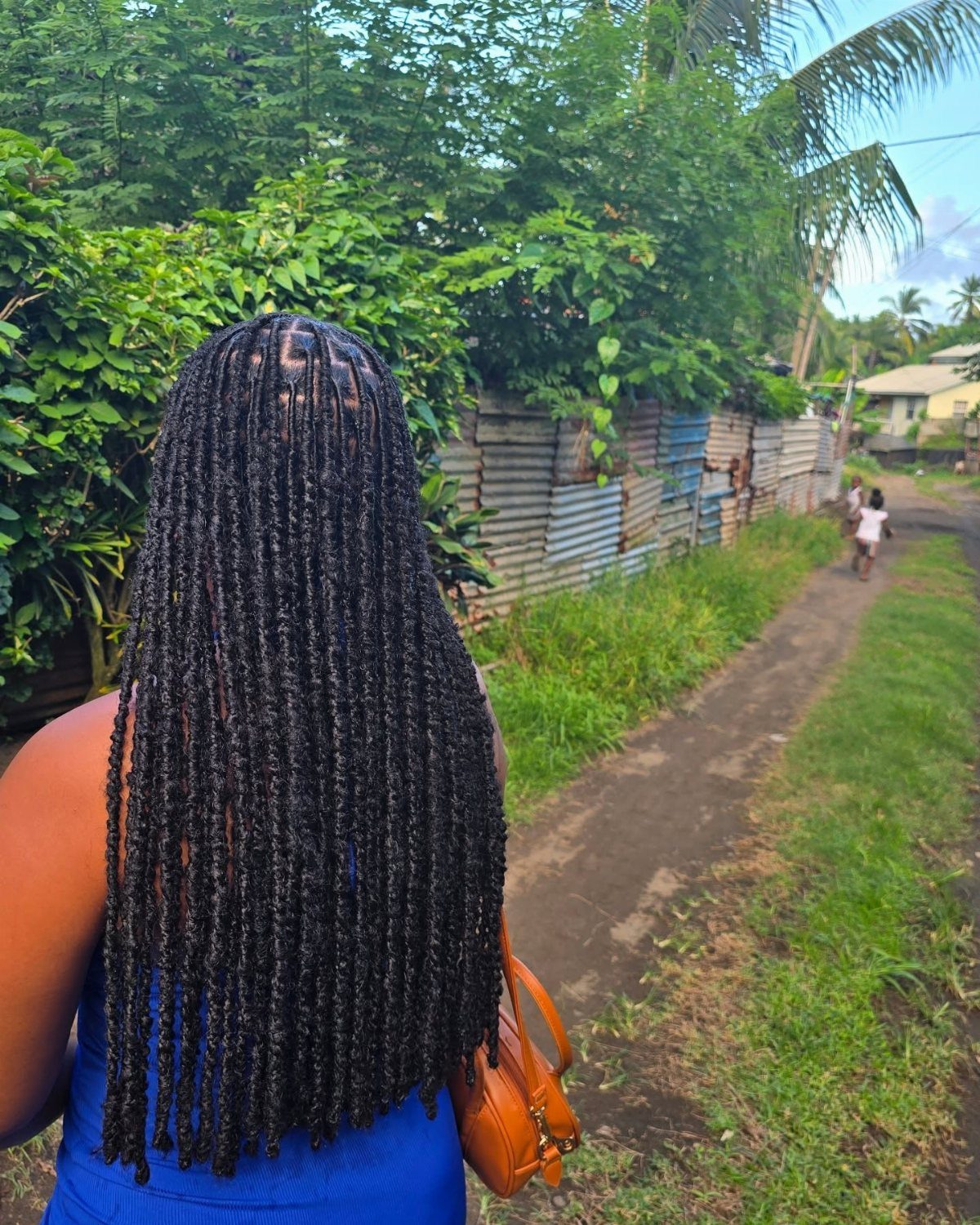 20 Thick Natural Hairstyles for Every Length and Mood 15 Long black faux locs on a person standing on a rural dirt path.