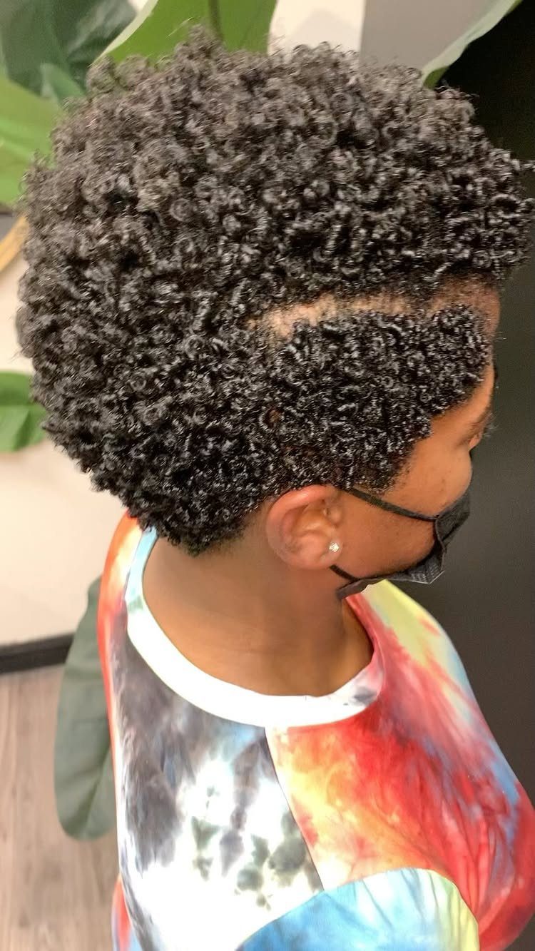 20 Thick Natural Hairstyles for Every Length and Mood 16 Person with thick, dark finger coil curls wearing a colorful tie-dye shirt.