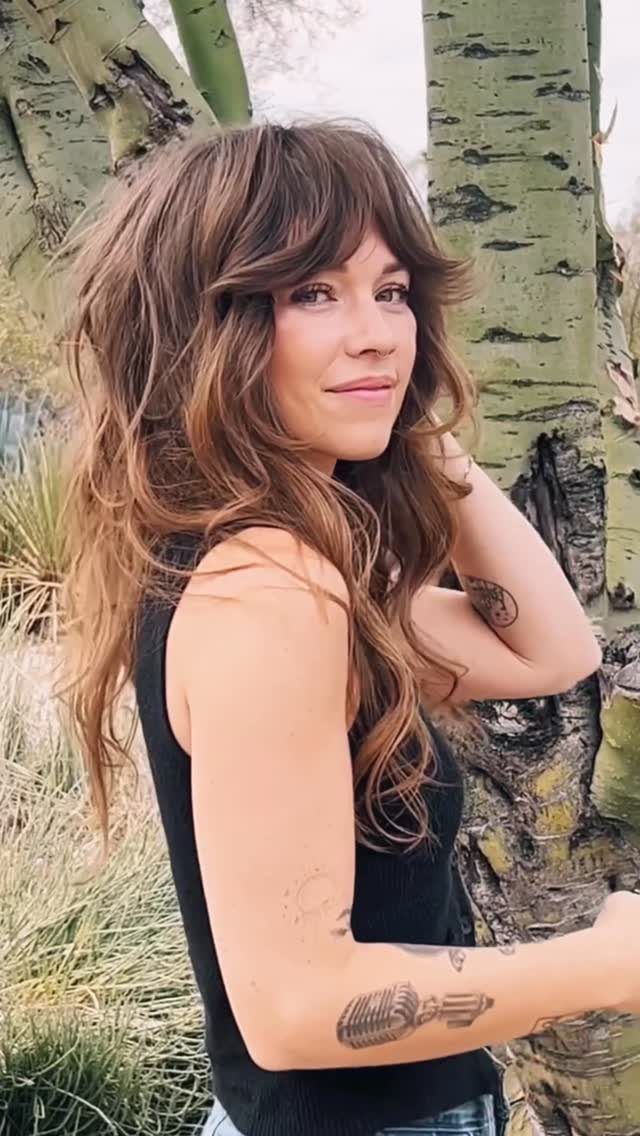 20 Thick Natural Hairstyles for Every Length and Mood 11 Woman with a thick brown soft shag haircut and bangs posing outdoors.
