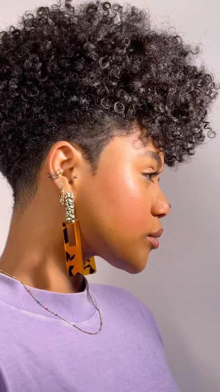 20 Thick Natural Hairstyles for Every Length and Mood 10 Woman with a tapered natural haircut featuring short sides and curly volume on top.