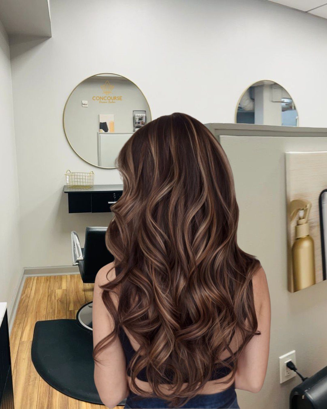 9 Toffee Caramel Hair Ideas for Brown and Blonde Bases 4 Woman with long wavy brown hair and caramel highlights in a hair salon