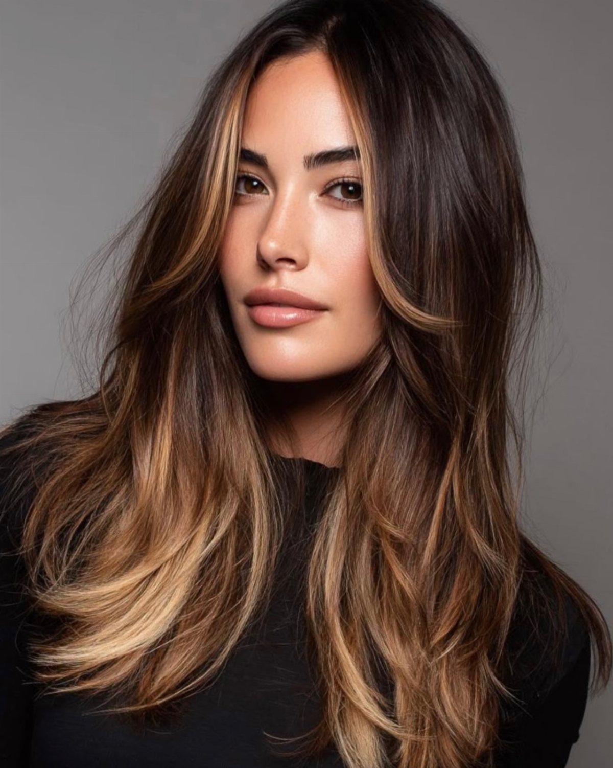 9 Toffee Caramel Hair Ideas for Brown and Blonde Bases 8 Woman with long layered hair in dark brown and toffee caramel tones.