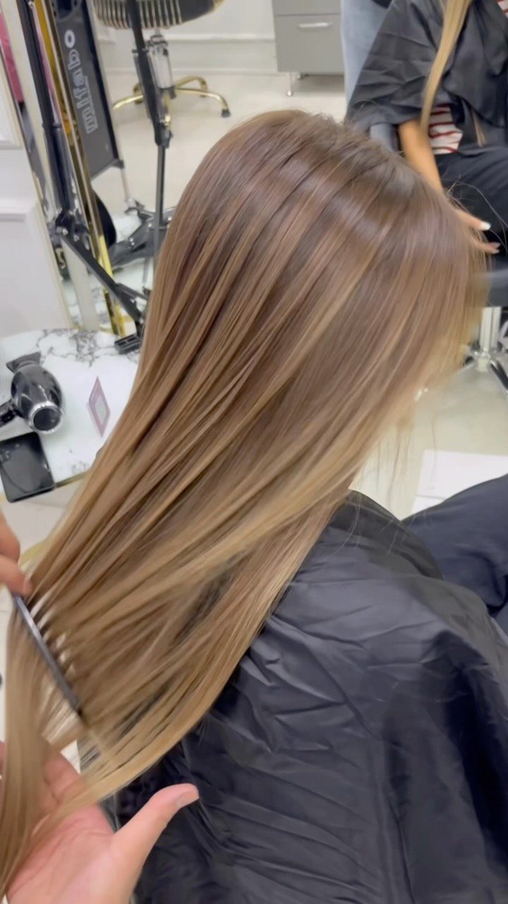 9 Toffee Caramel Hair Ideas for Brown and Blonde Bases 1 Long toffee caramel brown hair being combed in a professional hair salon.