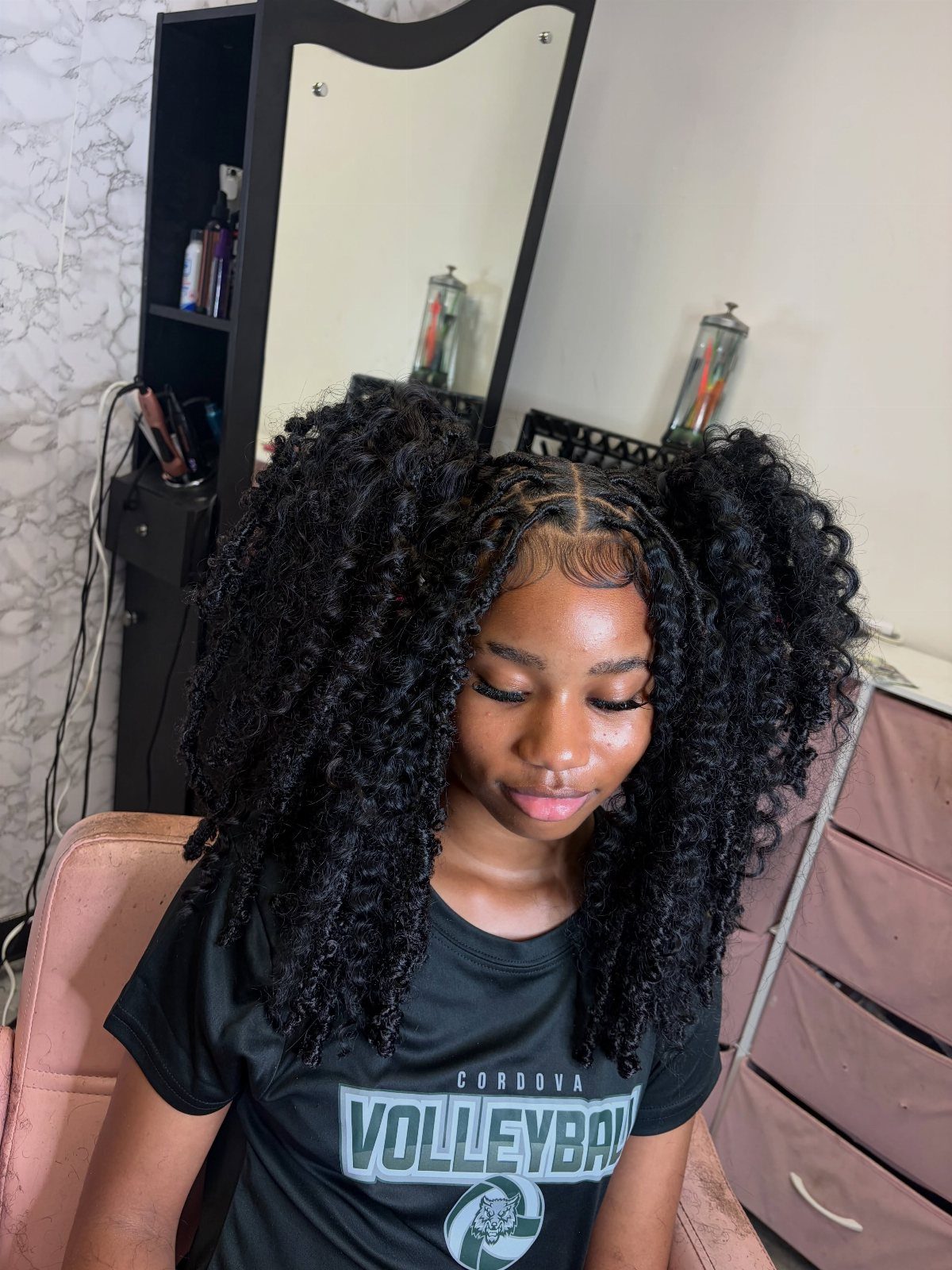 27 Trending Black Hairstyles, from Microbraids to Sisterlocks 8 Young Black woman with voluminous curly hair styled in two high afro puffs.