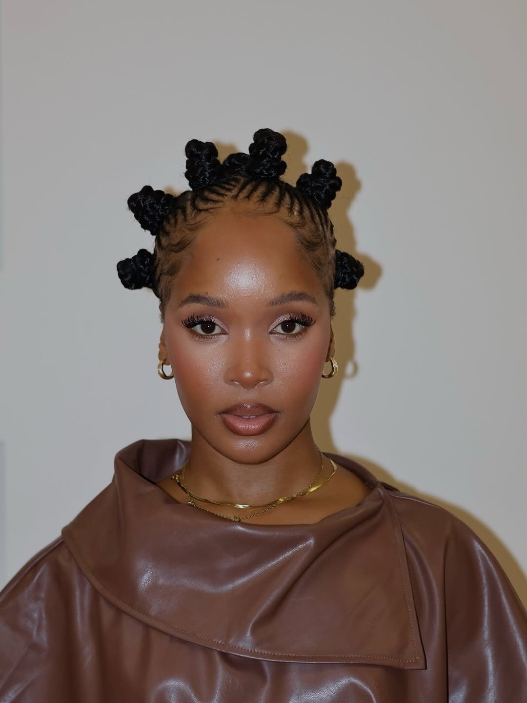27 Trending Black Hairstyles, from Microbraids to Sisterlocks 7 Woman with dark skin wearing her hair in Bantu knots and brown leather clothing.