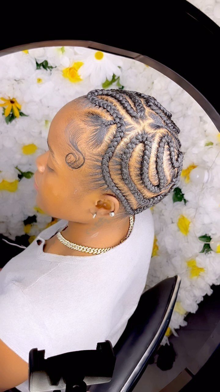 27 Trending Black Hairstyles, from Microbraids to Sisterlocks 2 Woman with an intricate braided updo and styled edges against floral background