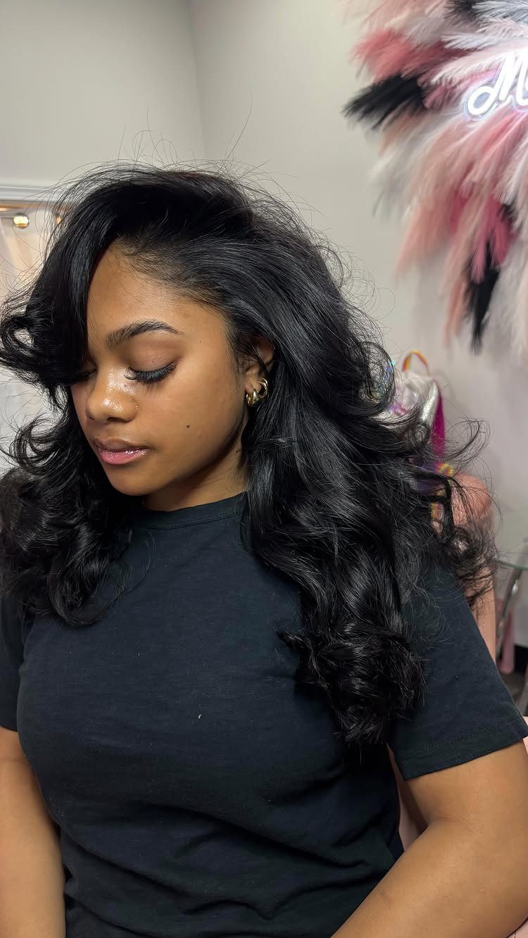 27 Trending Black Hairstyles, from Microbraids to Sisterlocks 26 Woman with voluminous shoulder-length curly black hair wearing a black t-shirt.