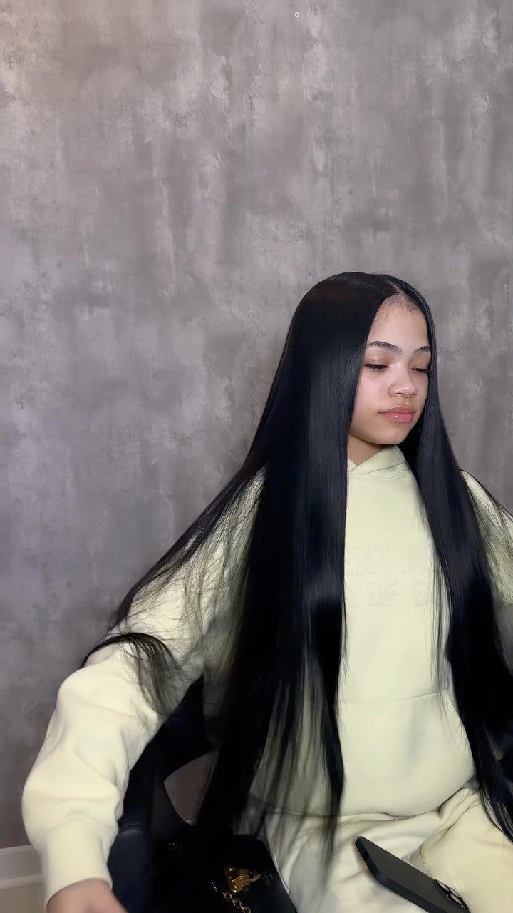 27 Trending Black Hairstyles, from Microbraids to Sisterlocks 17 Woman with long straight black hair wearing a light yellow hoodie and pants.
