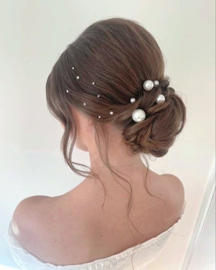 13 Trending Hair Style Ideas, from Curtain Bangs to Pixies 5 Brown hair styled in a low messy bun with white pearl hair accessories.
