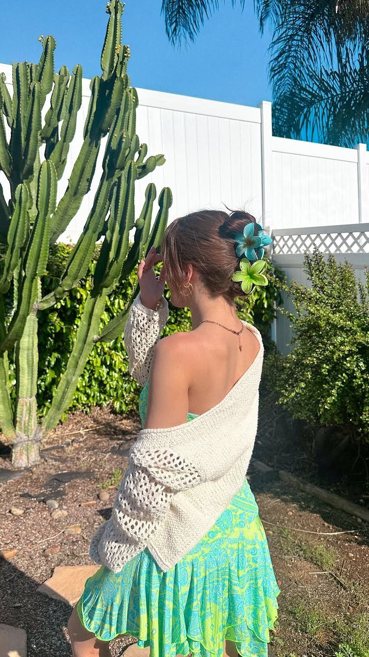 11 Updo Hairstyles for Casual Days and Easy Weekends 8 Woman with a floral bun hairstyle wearing a white crochet shrug and green dress.