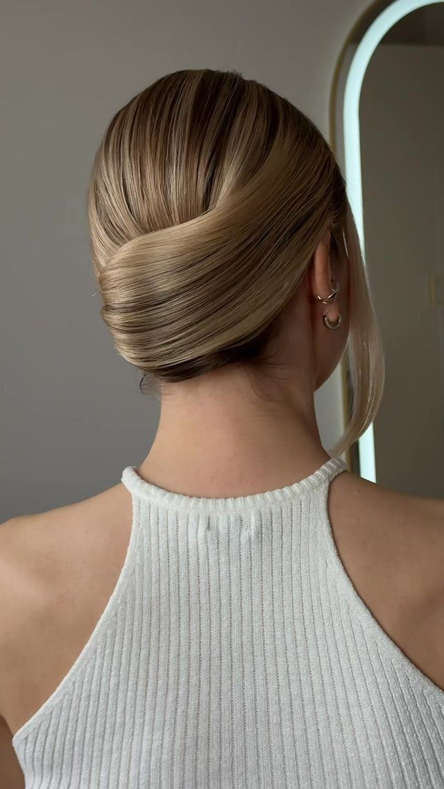 11 Updo Hairstyles for Casual Days and Easy Weekends 3 Blonde hair styled in a sleek French twist updo with a white top.