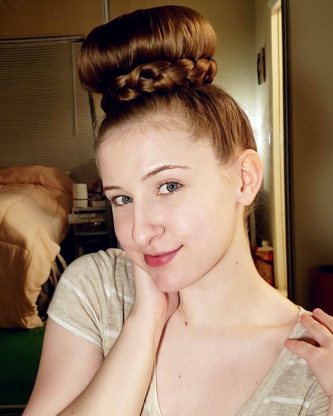 11 Updo Hairstyles for Casual Days and Easy Weekends 9 Woman with reddish-brown hair styled in a high braided updo bun posing indoors.