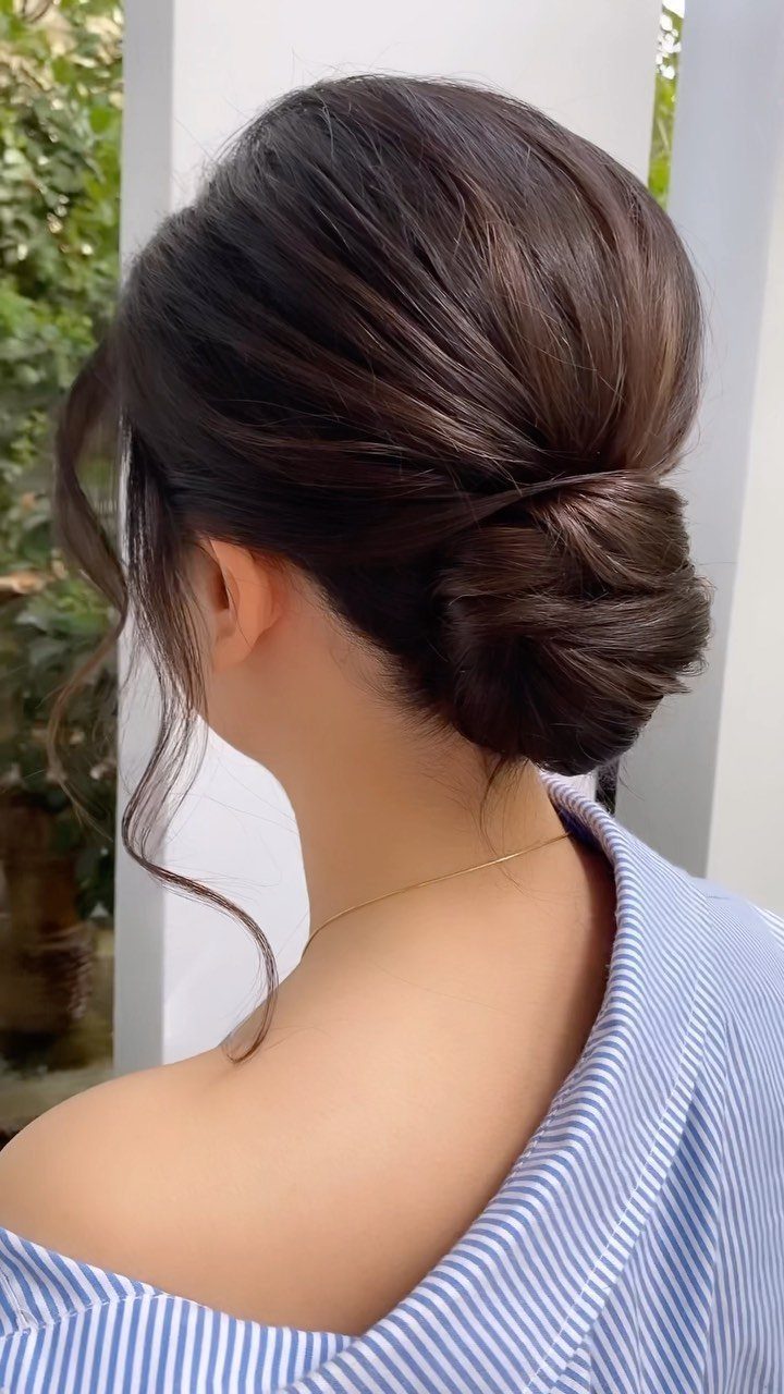 11 Updo Hairstyles for Casual Days and Easy Weekends 2 Woman with brown hair in a low twisted bun and loose face-framing strands.