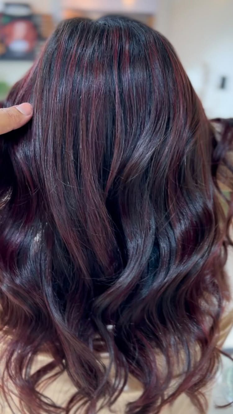 10 Violet Burgundy Hair Ideas for Dark to Bright Looks 10 Long wavy black hair with deep burgundy red highlights seen from behind.