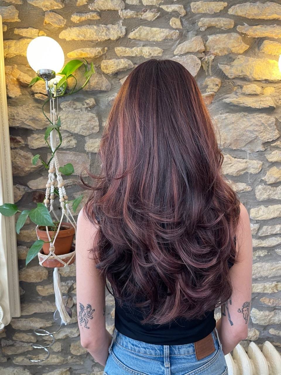 10 Violet Burgundy Hair Ideas for Dark to Bright Looks 5 Woman with long wavy dark chocolate hair and rich burgundy balayage highlights.