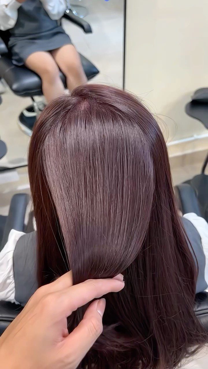 10 Violet Burgundy Hair Ideas for Dark to Bright Looks 3 Deep burgundy-violet hair being held up by a hand in a salon.