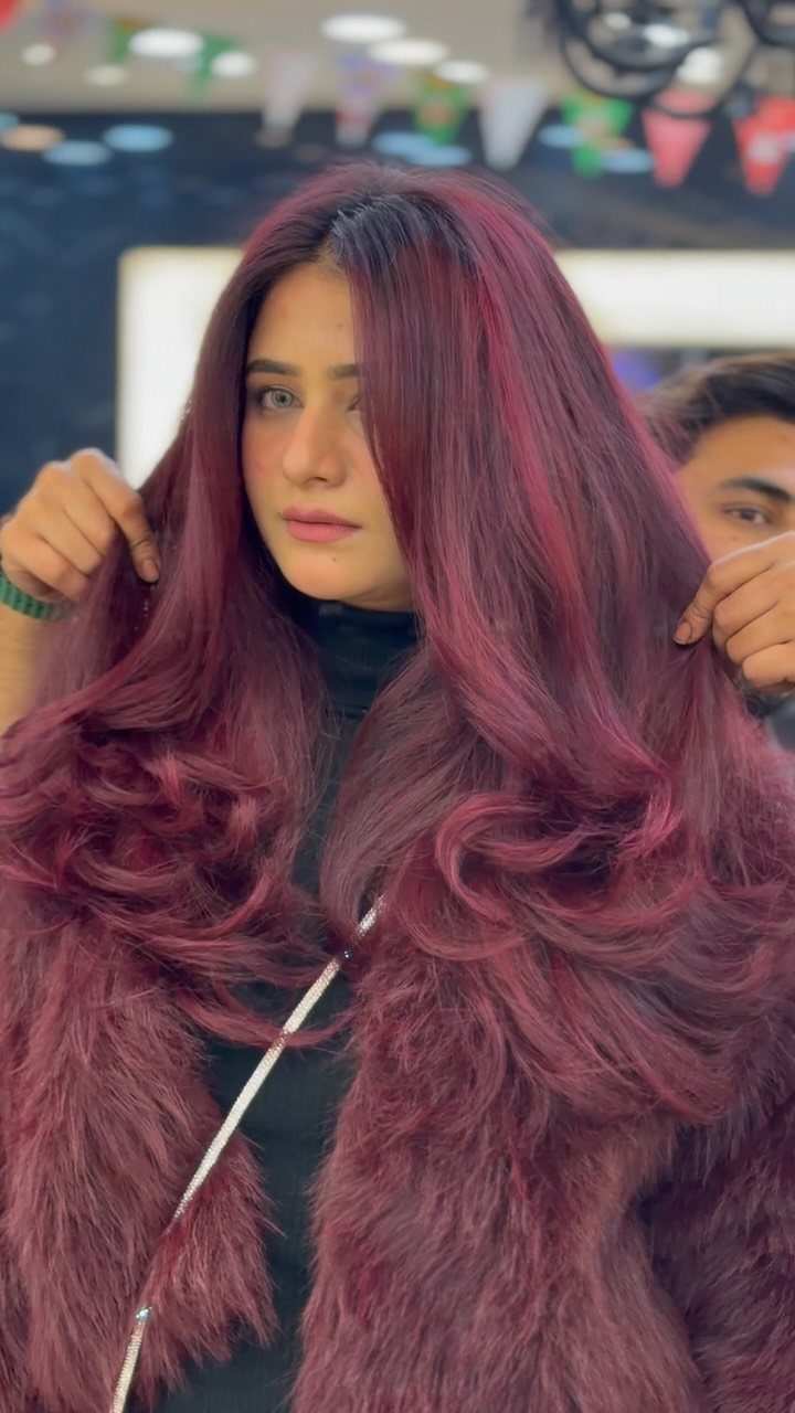 10 Violet Burgundy Hair Ideas for Dark to Bright Looks 9 Woman with long wavy plum burgundy hair wearing a matching faux fur coat.