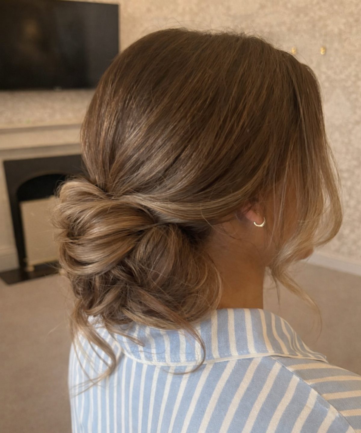 11 Wedding Guest Hairstyles for Medium Hair: Buns and Braids 1 Woman with light brown hair styled in a textured low chignon bun.