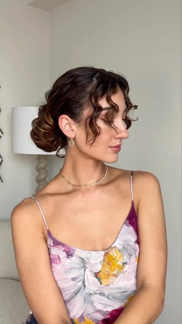 11 Wedding Guest Hairstyles for Medium Hair: Buns and Braids 7 Woman with curly brown hair styled in a low curly chignon updo.