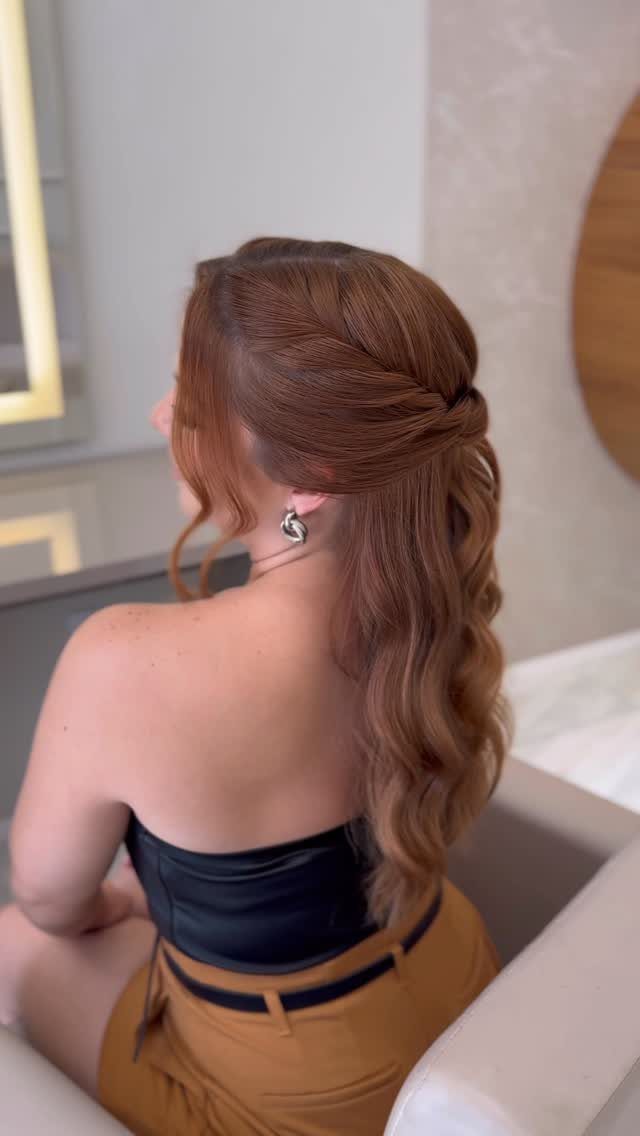 11 Wedding Guest Hairstyles for Medium Hair: Buns and Braids 2 Woman with reddish-brown hair in a half-up half-down style with flowing curls.