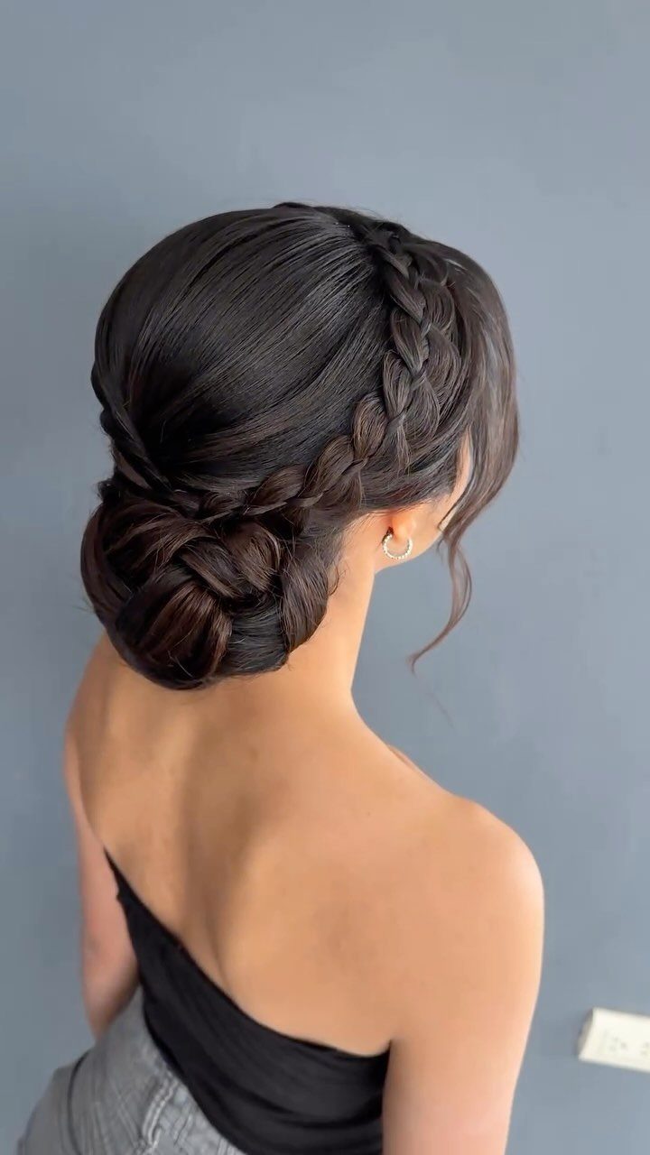 11 Wedding Guest Hairstyles for Medium Hair: Buns and Braids 8 Woman with dark hair in a low braided bun and side braid.