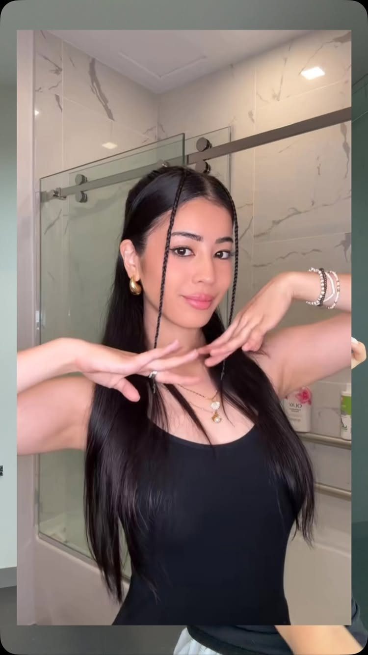 Y2K Braid Hairstyles: 9 Ideas From Butterfly Clips to Cornrows 5 Woman with long black hair and two thin baby braids framing her face.